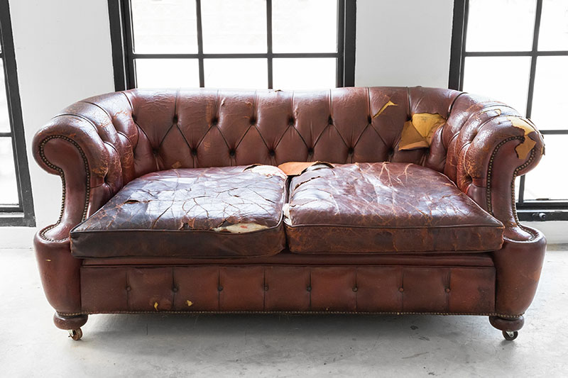Defective Old Brown Leather Sofa on White Room